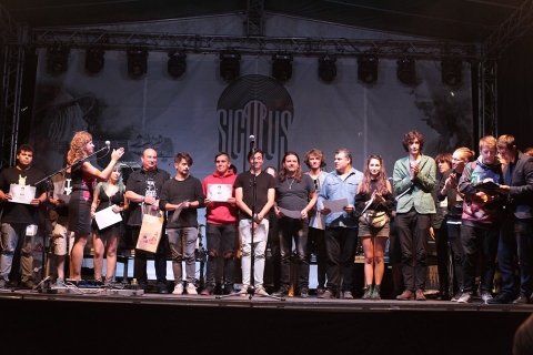 Kem�ny mezőny alakult ki a 7. SICULUS fesztiv�lon - 15 zenekar bemutatkoz�s�val, előad�sokkal, k�nyvbemutat�val, slam-produkci�val �s n�gy koncerttel, arch�v felv�telekből �s a tavalyi fesztiv�lon k�sz�lt felv�telekből �ll� fot�ki�ll�t�ssal, gyermekprogramokkal zajlott szeptember 6-8. k�z�tt a 7. SICULUS fesztiv�l Sz�kelyudvarhelyen a fesztiv�lhoz hangolt M�rton �ron t�ren. A zenei versenyre benevező zenekarok nagy sz�ma azt mutatja ma is hi�nyp�tl� �s fontos egy nyilv�nos f�rum, amely a k�lf�ldi rendezv�nyekre k�nyszer�lt zen�szeink, �nekeseink sz�m�ra itthon teremti meg a bemutatkoz�s �s az elismer�s lehetős�g�t. A SICULUS d�jakat elnyerő zenekarok sz�m�ra Erd�ly sz�mos nagysz�npad�n ad�dik lehetős�g a fell�p�sre, t�bb r�di�t�l �s telev�zi�t�l kapnak megh�v�st � �s ez a legfontosabb hozad�ka a saj�t dalszerzem�nyt �s magyar nyelvű dalsz�vegeket felkarol� seregszeml�nek. 
Az esem�nysorozat szombaton, szeptember 6-�n 16 �rakor szabadt�ri �nnep�lyes megnyit�val kezdőd�tt, ahol k�sz�ntőt mondott Bartalis Izabella, a Hargita Megyei Hagyom�nyőrz�si Forr�sk�zpont vezetője, majd Boros Zolt�n  nagyv�radi sz�rmaz�s�, Bukarestben �lő zeneszerző, rendező, a Rom�n Telev�zi� Magyar ad�s�nak volt zenei szerkesztője, a SICULUS fesztiv�l fel�j�t�s�nak egyik jelentős szak�rtő-t�mogat�ja. Felsz�lalt tov�bb� B�r� Barna Botond, a fesztiv�lt főt�mogat� Hargita Megyei Tan�cs aleln�ke, Antal L�r�nt, az RMDSZ Hargita megyei szen�tora �s Imre G�bor, az esem�nyt t�rsszervező Udvarhelysz�ki Egyeztető Tan�cs (UIET) eln�ke. Ezt k�vetően Sz�csi Zsolt műsorvezet�s�vel elkezdőd�tt a benevező zenekarok h�rom napig tart� versenye. 
P�nteken d�lut�n a C-sus-2, a Rafters, a Stonecrops �s az 8LightMinutes zenekarok mutattak be 3-3 dalt a verseny keret�ben, este pedig a nemideval�k c�mű zen�s slam poetry műsort hallhattuk, zene: Andr� Ferenc, sz�veg: Andr� Ferenc, Gy�rgy Evelin, J�rai-Szab� Rich�rd, T�falvi Előd. 
22 �rakor kezdőd�tt a tavalyi SICULUS fesztiv�l fő d�j�t elnyerő 4S Street zenekar nagy sikernek �rvendő koncertje, majd a Z�jg�ben zajlott a Fanky Jasonnel. 
Szombaton 14 �rakor a Siculus-szemle előad�saival folytat�dott a műsor: Vigh Be�ta szerzői jogokr�l, m�rkan�vbejegyz�sről tartott előad�st G�dri Ildik�, a Rom�n Telev�zi� Magyar Ad�sa szerkesztője moder�l�s�val. �A SICULUS fesztiv�lok m�ltja k�telez, mivel annyira r�gi m�rkan�vről van sz�, ez�rt tiszteletben kell tartani �s ennek megvannak a jogi eszk�zei.� - hangzott el t�bbek k�z�tt a jog�sz előad�s�n, ahol azt is megtudhattuk, a 8/1996-os szerzői jogokat szab�lyoz� t�rv�ny m�r r�gen elavult, hiszen idők�zben sz�ks�gess� v�lt a lemezgy�rt�k tev�kenys�g�nek �s az előad�k tev�kenys�g�nek a sz�tv�laszt�sa, �s az egykor meghozott jogszab�ly az internetes zenehaszn�lathoz �s a let�lt�sekhez sz�ks�ges elő�r�sokat nem tartalmazza.  A r�sztvevők arr�l is t�j�koz�dhattak, miben k�l�nb�znek a mor�lis jogok az anyagi jogokt�l, az exkluz�v �s a nem exkluz�v jogok �s mennyi időre �rj�k elő a jogv�delmi időtartamot. Rom�ni�ban is volt pr�b�lkoz�s a jogreformra, megvannak az elő�r�sai az egy�tteseket �rintő n�vbejegyz�snek, hangv�djegy, audi�-vizu�lis v�djegy lev�d�s�nek, �s azt is megtudtuk, hogy 2021-ig t�bb idev�g� uni�s t�rv�nyt kell m�g �rv�nybe l�ptetni. Hasznosnak bizonyult teh�t ez az előad�s, ak�rcsak az ezt k�vető, amelynek keret�ben Zilahi Csaba moder�l�s�val bemutatt�k Sar�ny Istv�n Kriterion K�nyvkiad�n�l tavaly megjelent k�tet�t a temesv�ri Garabonci�s egy�ttes t�rt�net�ről. A besz�lget�shez sz�mos anekdot�val �s inform�ci�val szolg�lt Vir�nyi Attila, a Metropol Group frontembere, aki a fesztiv�lon zsűritagk�nt volt jelen. P�rhuzamosan a v�rosi k�nyvt�rban a Rom�n Telev�zi� Magyar Ad�sa arch�vum�b�l a Siculus Fesztiv�l t�rt�net�t feleleven�tő arch�v felv�telek vet�t�se zajlott.
A szeml�t k�vetően hat tehets�ges zenekart hallgatott meg a versenyfesztiv�l zsűrije: a Szuver�n Kr�,a Szintaxis, a Kalandor, Luppinger Attila sz�l�git�ros, a Road Of Life �s a Hit Factory zenekarok l�ptek fel 3-3 zenei szerzem�nnyel. A szombat esti koncertprogram a k�zdiv�s�rhelyi Ego Sum zenekar fell�p�s�vel kezdőd�tt, ezt k�vette a kolozsv�ri Knock Out zenekar sz�kelyudvarhelyi bemutatkoz�sa, majd �jszak�ba ny�l� Retro buli volt a Felső G-ben.
Vas�rnap d�lut�n is volt SICULUS szemle, megh�vottja D�nes Ad�l volt, aki az Anna & The Barbies zenekar menedzsere �s G�dri Ildik� moder�l�s�val a Hogyan menedzselj�nk egy egy�ttest t�mak�rt fejtett�k ki, a besz�lget�sbe t�bb �rdeklődő is bekapcsol�dott. T�bbek k�zt felmer�lt itt az a probl�ma is, hogy Sz�kelyudvarhelyen nincs egy nagyobb sz�m� fiatalt befogad� koncert-klub-helys�g, egy�ltal�n a klub-�let is hi�nyzik, ahol a kezdő zenekarok bemutatkozhatn�nak. Megtudtuk azt is, hogy az olyan zenekarokn�l, ahol nincs lehetős�g arra, hogy egy menedzser felv�llalja az egy�ttes p�lyafut�s�nak szervez�s�t, ott a zenekar minden tagja egyenk�nt mindent meg kell tegyen a befut�s �rdek�ben. Term�szetesen a dalsz�veg is sz�m�t: ne legyen elcs�pelt, legyen erős �s egyszerű �zenete, de a zenekarnak az arculati k�rd�sekben is fontos d�nt�seket kell meghozni. 
A vas�rnapi versenymeghallgat�sra �t kiv�l� zenekar maradt: a T�rerő, az Urania, a Full Screen, a KentaurSoul �s A Csajod. A szakmai zsűri tagjai � Bartalis Izabella zenepedag�gus, a Hargita Megyei Hagyom�nyőrz�si Forr�sk�zpont igazgat�ja, Vir�nyi Attila nagyv�radi sz�rmaz�s� zen�sz, a Metropol egy�ttes frontembere, Zilahi Csaba, a Kolozsv�ri R�di� zenei szerkesztője, az erd�lyi git�rt�borok egyik kezdem�nyezője �s szervezője, Bal�zs Imre J�zsef Kolozsv�ron �lő, Sz�kelyudvarhelyen sz�letett k�ltő, irodalomkritikus, szerkesztő, irodalomt�rt�n�sz, a KORUNK főszerkesztő-helyettese, Orosz P�l Levente, r�di�s szerkesztő, a Transilvanyum dalszerzője �s �nekese,  Butu Arnold, a Palma Hills egy�ttes frontembere, Andr� Ferenc, k�ltő, slammer, a kolozsv�ri Helikon foly�irat szerkesztője, akik az este 9 �rakor kezdődő d�jkioszt� g�l�ig meghozt�k a d�nt�st.
A SICULUS-g�la ki�rt�kelőkkel kezdőd�tt, felsz�lalt Bartalis Izabella menedzser a főszervező r�sz�ről, tov�bb� Boros Zolt�n �s Vir�nyi Attila �rt�kelte a rendezv�nyt. Hargita Megye Tan�csa aleln�ke is hangs�lyozta a versenyfesztiv�l jelentős�g�t, majd ő adta �t a főd�jas zenekarnak j�r� 1000 eur�s jutalmat. 
A Siculus Fesztiv�l nagyd�j�t a sepsiszentgy�rgyi T�rerő zenekar nyerte el, �v� lett az ezer eur�s főd�j, illetve a Kincses Kolozsv�r egy�ttes megh�v�sa a 2020. �vi Kolozsv�ri Magyar Napokon val� fell�p�sre. A nagyd�j mellett n�gy tov�bbi, egyenk�nt 500 eur� p�nzjutalommal j�r� d�jat osztott ki a szakmai zsűri: a legjobb zenei szerzem�ny a temesv�ri 8Light Minutes zenekar� lett; a legjobb dalsz�veg�rt j�r� elismer�st a kolozsv�ri A Csajod egy�ttes kapta; a legjobb �nekes d�j�t Mosne�g Anna-M�ria, a borsz�ki Kalandor zenekar �nekese vette �t; a legjobb hangszersz�list�nak j�r� elismer�st a cs�kszeredai Szuver�n Kr� basszusgit�rosa, J�nos L�szl� vehette �t. A gyergy�szentmikl�si Full Screen egy�ttes lehetős�get kapott arra, hogy st�di�felv�telt k�sz�tsen az RTV Magyar Ad�s�ban. A kolozsv�ri Szintaxis, a sz�szr�geni KentaurSoul �s a marosv�s�rhelyi Urania egy�ttesek a Sz�kelyudvarhelyi V�rosnapokon kaptak fell�p�si lehetős�get., a gyergy�szentmikl�si Rafters egy�ttes a Kov�sznai V�rosnapokon l�phet fel. A borsz�ki Kalandor egy�ttest a hamarosan megrendez�sre ker�lő sz�kelyudvarhelyi Őszi V�s�rra h�vt�k meg. Mind a 15 zenekar, amely bejutott a SICULUS fesztiv�l m�sodik fordul�j�ra, ingyenes bel�p�st nyert  az Anna & The Barbies zenekar �ltal �pusztaszeren, a csod�s Akhal M�nes term�szetv�delmi ter�let�n szervezett Hell� Ugar! elnevez�sű fesztiv�lra, ahol a SICULUS nagyd�j�t elnyerő zenekar fell�p�si lehetős�get is nyert. 
A d�jkioszt� �nneps�g ut�n vas�rnap este a fesztiv�l az Anna & The Barbies zenekar szabadt�ri koncertj�vel z�rult.     

A SICULUS fesztiv�l partnerei: Sz�kelyudvarhely V�ros Polg�rmesteri Hivatala, Sz�kelyudvarhely Művelőd�si H�za, Udvarhelysz�k Kultur�lis Egyes�let, m�diapartnerek: a Rom�n Telev�zi� Magyar Nyelvű Ad�sa, Erd�lyi Magyar Telev�zi�, Kolozsv�ri R�di� Magyar Ad�sa, a  Hargita N�pe, a Transversum SRL �s az Erd�ly.Ma. 
T�mogat�k: Bethlen G�bor Alap, az RMDSZ �s a Communitas Alap�tv�ny. V�llalkoz�i t�mogat�sok: Stage & Ledtech Kft, G�b� term�k, Amigo & Intercost v�llalat  �s a sz�kelyudvarhelyi Hotel Tranzit sz�ll�. 

Rem�lj�k, j�vőre is ilyen minős�gi zenekari megm�rettet�sben �s SICULUS fesztiv�l-programban lesz r�sz�nk!
