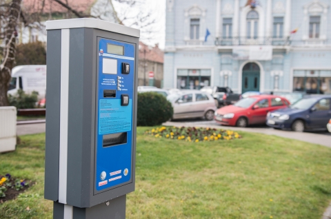December elejétől újra fizetőssé válik a parkolás Kézdivásárhelyen - A december elején érvénybe lépő fizetős parkolás a Gábor Áron teret, a Petőfi Sándor utca Boldog Özséb templomig tartó útszakaszát, a Kaszárnya előtti parkolót, a Függetlenség utcát, az Ady Endre utcát, a Kossuth Lajos teret, a Márton Áron teret, a Szőcs József utcát, valamint a Dózsa György utat érinti. A parkolásért reggel fél kilenc és délután fél öt között kell fizetni, kerékbilincselés nem lesz, aki pedig elfelejt jegyet váltani, egy napijegy megvásárlásával kiválthatja büntetését.
Kézdivásárhely Helyi Tanácsa a májusi soros tanácsülésen határozott arról, hogy szükséges a fizetős parkolás visszavezetése Kézdivásárhely néhány közterületére. Az intézkedésre azért van szükség, mert napközben lehetetlenné vált a parkolás Kézdivásárhely központjában, valamint a főtérre bevezető részeken. A tanácsosok a korábbihoz képest egy jóval megengedőbb határozatot dolgoztak ki, amelynek célja a rendteremtés.
A Helyi Tanács új határozata négyféle bérletet kínál: lesz havi és éves, jogi személyek számára lefoglalható parkolóhely, lakóbérlet és fogyatékkal élők számára kiállított bérlet is. A havi és éves bérletet magán- és jogi személyek is igényelhetik, a lakóbérletet csak a fizetős parkoló zónájában lakók válthatják ki. A fogyatékkal élők és azok törvényesen megnevezett kísérői ingyenesen használhatják a parkolókat, elsősorban a számukra kijelölt helyeket. A lakóbérletet az önkormányzattól lehet igényelni a személyigazolvány és a jármű igazolványának felmutatásával, de csak abban az esetben, ha nem áll rendelkezésre garázs vagy más parkolási lehetőség. A következő zónákban lakók igényelhetnek lakóbérletet: Gábor Áron tér, Márton Áron tér, a 7-től 23-as Udvarterek lakói, a 39-től 46-os Udvarterek és a 69-es Udvartér lakói. A bérletek Kézdivásárhely polgármesteri hivatalának Adó és Illeték Irodájából szerezhetőek be.
A parkolás munkanapokon 8.30 és 16.30 között lesz fizetős, szombaton és vasárnap, valamint ünnepnapokon és munkaszüneti napokon ingyenes. A parkolójegyet az automatából lehet megvenni, de SMS-ben is lehetőség van a fizetésre, a táblákon feltüntetett mód szerint. SMS-ben történő fizetés esetében egy órás és egy napos jegy váltása lehetséges. Az ügyfél megerősítő SMS-t kap, amely tartalmazza az időtartamot és az SMS költségét. Teherszállító járművek szabadon parkolhatnak munkanapokon 8.30 és 11.00 óra között, fizetési díj nélkül. A megadott időintervallumon túl parkolójegyet kell váltaniuk. A taxisoknak kötelező az éves bérlet, ennek értéke 120 lej egy évre.
Amennyiben valaki nem vált jegyet vagy érvénytelen jeggyel állomásozik, büntetést kap. A büntetés kifizetésére 48 óra áll az autótulajdonos rendelkezésére, értéke pedig egy napijegy ára, azaz 10 lej. Ha 48 órán belül nem fizeti be a napidíjat, a büntetés 150–300 lejre nő, esettől függően.
Tarifák
A parkolási díjak a következőképpen alakulnak: egy óra parkolás a Gábor Áron téren két lejbe kerül, a további fizetős zónákban egy óráért egy lejt kérnek el. A napidíj értéke 10 lej. Aki SMS-ben vált jegyet, annak egy óra 0,40 euró + áfába kerül, a napidíj 2,1 euró + áfa. A havi bérlet magánszemélyek számára 35 lej, jogi személyek részére 35 lej + áfa. Az éves díj 250 lej magánszemélyek részére és 250 lej + áfa jogi személyek számára. Aki állandó parkolóhelyet szeretne váltani (csak jogi személyek jogosultak), azok évi 600 lej + áfa kifizetésével tehetik meg. A lakóbérlet értéke 25 lej/hónap és 120 lej/év.
A fizetős parkolás kivonatolt változata a www.kezdi.ro honlapról érhető el, ugyanitt található meg a részletes tanácshatározat is.
I. Fejezet: Általános rendelkezések
Bérlettípusok:
- Havi vagy éves – fizikai személyek számára
- Parkolói bérlet a lefoglalt helyre vonatkozóan – jogi személyek számára
- „Riverán” bérlet – „Lakóbérlet”, aki abban a zónában laknak, ahol a parkolásért fizetni kell
- Fogyatékkal élők számára
A parkolói engedély a lefoglalt helyre vonatkozóan a következő intézmények számára engedélyezett: közintézmény, szállodák, kereskedelmi egységek, sportlétesítmény, bankok – ezen intézmények számára az Önkormányzat határozza meg a bérleti díjakat.
Ahhoz, hogy helyet tudjanak lefoglalni az előbb említett intézmények, kérést kell letenniük az Önkormányzat fele, a kért zónában az összparkolók 15%-át kaphatják meg.
Havi vagy éves bérlettel rendelkező személyek az összes fizető zónában parkolhatnak.
A helyhez kötött bérletet előzetesen kell megszerezni, ezt az Önkormányzat adóhivatalában lehet kifizetni, vagy banki átutalással. Amennyiben a banki átutalásra esik a választás, az engedélyt csak a Kincstárból kapott számlakivonat felmutatása után kaphatja meg az illető.
A jogi személyeknek a helyhez kötött engedélyükkel jogukban áll blokkolni saját helyüket. Az engedély 1 évre szól.
Az általános bérlet minimum 1 hónapra és maximum 1 évre szólhat.
A bérlet kizárólag egy autóra érvényes, a rendszámtáblát a bérlet tartalmazza, kivételt képez a következő két eset:
- Pénzügyi lízingszerződés, amikor a tulajdonjog átruházása abban a peridósban történik
- Tulajdonjog átruházása, öröklés, adományozás az előfizetés érvényessége ideje alatt.
Azok a fizikai személyek, akik azokban a zónákban laknak, ahol fizetős a parkolás, engedélyt kell kiállíttatniuk, amelyhez a következő dokumentumok szükségesek:
- Személyazonossági másolat, a jármű igazolványa
- Lakóbérlet csak akkor váltható ki, ha az illető teljesítette adókötelezettségét.
- Bérletet előzetesen kell megszerezni, ezt az Önkormányzat adóhivatalában lehet kifizetni, vagy banki átutalással. Amennyiben a banki utalást választja az illető, az engedélyt csak a Kincstárból kiváltott számlakivonat felmutatása után lehet kiváltani.
A lakóbérlet csak olyan fizikai személyeknek jár, akiknek nincs egyéb lehetősége (garázs, udvar, stb.). Csak egy járműre érvényes, rendszámtábla megadása kötelező.
Azon személyek, akiknek a lakása két utca között helyezkedik el, a kettő küzül pedig csak az egyik rendelkezik fizetős parkolóval, nem kaphatnak lakóbérlet.
A következő zónákban lakók igényelhetnek lakóbérletet: Gábor Áron tér, Márton Áron tér, a 7-től 23-as Udvarterek, a 39-től 46-os Udvarterek és a 69-es Udvartér.
A fogyatékkal élő személyek számára, vagy azon fizikai személyek számára, akik az előbb említett személyeket szállítják, díjmentes a bérlet igénylése.
Az előbb említett bérlettel meghatározatlan időre engedélyezett a várakozás, viszont kötelező feltüntetni jól látható helyen az egyezményes nemzetközi jelzést, amelyet a következő dokumentumokkal lehet kiváltani az Önkormányzat adóhivatalánál:
- Kérés
- A fogyatékossági besorolásról szóló határozat
- Személyi igazolvány másolat
- A felülvigyázói engedély
- Elsősorban azokat a helyeket vehetik igénybe, amelyek a fogyatékkal élők számára vannak fenntartva. Csak egy járműre érvényes, rendszámtábla megadása kötelező.
- Amennyiben a tulajdonos elveszíti bérletét, kérhet hitelesített másolatot az Önkormányzat adóhivatalából.
II. Fejezet: Speciálisan kijelölt helyek adminisztrálása
- A tömegközlekedési járművek a számunkra kijelölt helyre állhatnak meg.
- A bérletek díját a helyi tanács határozza meg évente.
- A parkolás időtartama: munkanapokon 8.30–16.30 között. Szombaton és vasárnap, ünnepnapokon, munkaszüneti napokon ingyenes a parkolás.
- Fizetési lehetőségek: parkoló automata vagy SMS
III. Fejezet: Fizetési lehetőségek és feltételek
- A parkolójegyet az automatából lehet megvenni.
- SMS-ben is lehetőség van a fizetésre, a táblákon feltüntetett mód szerint. SMS-ben történő fizetés esetében egy órás és egy napos jegy váltása lehetséges.
- Az ügyfél megerősítő SMS-t kap, amely tartalmazza az időtartamot és az SMS költségét.
- Teherszállító járművek szabadon parkolhatnak munkanapokon 8:30 és 11:00 óra között, fizetési díj nélkül. A megadott időintervallumon túl parkolójegyet kell váltaniuk.
- A taxisoknak kötelező az éves bérlet, ennek értéke 120 lej egy évre.
A következő járművek mentesek a parkolási díj alól:
- diplomáciai testületek járművei
- rendőrség, helyi rendőrség, csendőrség, a SPP, a tűzoltók, a mentők és a SMURD – küldetésben
- a fogyatékkal élő személyek
- az Önkormányzat tulajdonában lévő járművek
- a város központjába látogató turistabuszok, a számukra kijelölt helyeken
IV. Fejezet: Szabályok és szankciók
- A büntetés kifizetésére 48 óra áll az autótulajdonos rendelkezésére. A büntetés értéke 10 lej, ez az információ a büntetőcédulán is szerepel.
- Az ellenőrzés ideje alatt a járművezetőnek kötelessége megmutatni személyigazolványát, az autó igazolványát, valamint a forgalmi engedélyt.
- Ezen rendelet betartásának ellenőrzését végző helyi rendőrök kötelesek felmutatni szolgálati igazolványukat.
- Ha a járművezető megtagadja a dokumentumok benyújtását, jogsértési szankciót követ el.
Ha jogi személy tulajdonában álló járművel történik szabályszegés, a tulajdonos postán köteles elküldeni a szabálysértő sofőr adatait. Ha elmulasztja vagy hamis adatokat küld, jogsértést követ el. Ilyen esetben a következő adatokat kell elküldeni:
- román állampolgárok esetében:
- keresztnév és vezetéknév;
- tartózkodási engedély – esettől függően;
- egyéni személyazonosító szám;
- személyigazolvány szám.
- külföldi állampolgárok esetében:
- keresztnév és vezetéknév;
- útlevél vagy más személyi igazolvány száma, a kibocsátó állam és a dokumentum kiadásának dátumát.
- jogi személyek esetében:
- a regisztrációs igazoláson feltüntetett név;
- a székhely;
- az egyedi regisztrációs kód vagy a cégjegyzékszám;
- a képviselő személy azonosítási adatai;
- a bankszámla.
Esettől függően, büntetésben részesülhetnek azon járművezetők, fizikai vagy jogi személyek, akik(nek):
a) a parkolási díjat nem fizették ki,
b) a parkolási jegyet nem tették látható helyre,
c) a fogyatékkal élők számára fenntartott parkolóhelyeken álltak meg;
d) meghaladják a parkolási jegy idejét;
e) a mezőgazdasági gépek, az ipari járművek, a 3.5 tonnát meghaladó össztömegű járművek, teherautók,
f) nem a kijelölt helynek megfelelően parkoltak,
g) ha lejárt engedéllyel vagy egy másik személy számára kiadott engedéllyel parkolnak,
h) ha a fizetős parkolóhelyet akadályozzák,
i) más számára megjelölt parkolóhelyet foglaltak el,
j) ha a Városháza engedélye nélkül kereskedelmi tevékenységet végeznek a fizetős parkolóban,
- Az Önkormányzatnak jogában áll helyeket lefoglalni pl. rendezvények kapcsán, aki ezt nem tartja tiszteletben és elfoglalja az előbb említett helyeket, szintén büntetés jár.
A kihágások a következő pénzbírsággal büntetendők:
a) 150 lej – b), c), d), e), f), g), h) pontok;
b) 300 lej – (a), (i), (j), (k) pontok.
- A kihágást elkövető fél számára legfeljebb 48 óra áll rendelkezésére, hogy rendezze a büntetés kifizetését.
V. Fejezet: Tarifák
- A 2017-es naptári évre vonatkozó járművek parkolási díja a következő:
Parkolásdíjak:
a) óradíj: a Gábor Áron téren 1 óra parkolás 2.00 lejbe kerül, Kézdivásárhely közterületén található további fizetős zónáiban 1 óra parkolás 1.00 lejbe kerül.
b) napidíj 10 lej
c) SMS-díjak: 0,40 euro/óra + ÁFA, napidíj 2,1 euro/nap + ÁFA.
Bérletek:
a) havidíj: 35 lej magánszemélyek számára és 35 lej + ÁFA jogi személyek részére;
b) éves díj: 250 lej magánszemélyek részére és 250 lej + ÁFA jogi személyek számára;
Parkolási engedély:
a) parkolási engedély helyfoglalással jogi személyek részére: 600 lej + ÁFA/év;
b) lakók számára kiállított parkolási engedély (csak magánszemélyek részére): 25 lej/hó és 120 lej/év.