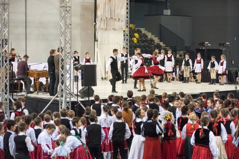 Újabb sikeres évadot zár a Háromszék Táncegyüttes 2019-ben - Újabb sikeres évadot zár a Háromszék Táncegyüttes 2019-ben
Számtalan kiszállás, több nemzetközi turné, jó pár színvonalas rendezvény és két új bemutató is színesítette a Háromszék Táncegyüttes 2018/2019-es évadját. Az elmúlt tíz hónap során összesen 101 alkalommal állt színpadra a társulat, melyek közül 20 esetben az ország határain túl is népszerűsítette az erdélyi folklór, népi hagyományaink sokszínűségét.
Vágják az erdei utat… – új folklórműsorral jelentkezett a Háromszék Táncegyüttes
Öt év, nyolc táncszínházi produkció, valamint két gyermekelőadás premierje után, szeptember közepén, az évad első bemutatójaként ismét hagyományos folklórműsort állított színpadra az együttes. Az Ivácson László által rendezett Vágják az erdei utat… című produkció az első világháború néprajzi vonatkozásait dolgozza fel.
„A Háromszék Táncegyüttes legújabb folklórelőadása keserű-édes emlékezés, egy olyan táncos-zenés barangolás, amelyben a gyergyói, a küküllő-menti, a sajó-menti és az észak-mezőségi tájegységek magyar, román, illetve cigány népzene és néptánc világába utaztatják a nézőt. Száz évet vissza az időben.” – olvasható a szinopszisban.
A Vágják az erdei utat… című folklórműsor sikerét igazolja, hogy a szeptemberi bemutató óta összesen 37 alkalommal játszotta a társulat ezt az előadást, így határozottan az évad legsikeresebbnek mondható produkciójáról van szó. A számtalan belföldi kiszállás mellett, a helyi közönség is gyakorta láthatta a darabot, de az országhatárokon túlra is sikerült eljuttatni az első világháború hangulatát idéző és a korszak folklorisztikai jelentőségét hangsúlyozó előadást. Ráadásul a műsor sikerét méltán igazolja az is, hogy március 15-én, a nemzeti ünnep alkalmából a budapesti a Magyarság Házában teltház előtt, állótapssal üdvözölték az Ivácson László rendezte produkciót.
Világhírű Redever – táncjáték gyerekeknek (és nem csak)
A 2018/2019-es évad második bemutatójaként február 26-án újabb gyerekeknek szánt produkciót mutatott be a Háromszék Táncegyüttes. A Világhírű Redever című táncjáték Molnár Szabolcs, Fazakas Misi és László Csaba alkotói szándékát foglalja össze.
„A Háromszék Táncegyüttes gyerekelőadásainál most már egyfajta védjeggyé vált, hogy interakcióval szólítjuk meg a legkisebbeket. Én személy szerint nagyon fontosnak tartom az ilyen típusú előadásokat, hiszen azt gondolom, hogy a tánc hihetetlenül alkalmas arra, hogy megszólítsa őket, illetve úgy vélem, hogy nagyon sok gyerek a bábszínház után ezen produkciók révén kerülhet és maradhat a színház közelében.” – nyilatkozta Fazakas Misi társrendező a bemutató előtti időszakban.
Bár az említett táncjáték csak az évad második felében volt bemutatva, hiánypótló jellegét és jogos népszerűségét igazolja, hogy ilyen rövid idő alatt is mintegy 22 alkalommal tűzte műsorra az együttes. Nem utolsó sorban egy májusi kiszállássorozat keretében a megye különböző településein élő közönséghez is sikerült eljuttatni a kedvelt gyerekelőadást.
Számok és adatok
A Háromszék Táncegyüttes a 2018/2019-es évadban összesen 101 lépett színpadra, amelyek közt a két új bemutató mellett további műsoron tartott produkciók is szerepeltek. Így a mindenkori közönség a már említett Vágják az erdei utat… és a Világhírű Redever című darabokon túl, az előző évadban bemutatott AranyAsszonyok című rituális folklórelőadást, valamint a Két kezem forgatta, szívem táncoltatta, a Mundruc és a Szerencsekrajcár című előadásokat is láthatta az elmúlt tíz hónap során.
Az együttes a különböző megyei, illetve az erdélyi helyszínek mellett a külföldi színpadokokon is gyakorta bemutatkozott, hiszen az évad során összesen 20 különböző határon túli településen lépett fel. A nemzetközi turnék alkalmával például Magyarországra, Ukrajnába és Szlovákiába is eljutott a társulat, így többek közt Ungváron, Zselízen, Budapesten, Budakalászon, Miskolcon, Egerben, Nyíregyházán, Pápán, Balatonakalin, Tiszakécskén és Győrben is láthatók voltak a Háromszékes előadások – több esetben neves táncfesztiválok és rangos rendezvények meghívottjaként.
Fontos mérföldköve volt a Háromszék Táncegyüttes idei évadjának az immár 30. alkalommal megszervezett sepsiszentgyörgyi Népzene- és Néptánctalálkozó (NNT) is, amelyre november 9-én és 10-én került sor. A rendezvény fő programsorának ez alkalommal rendhagyó módon a Sepsi Aréna adott otthont, ahol nemcsak a Kovászna megyei gyermek és ifjúsági néptáncegyüttesek mutatkozhattak be, hanem színpadra lépett a Magyar Állami Népi Együttes, gyermekkoncertet adott a Kolompos együttes, valamint ezúttal is több néprajzi tájegységről érkeztek hagyományőrző táncosok és zenészek. Mindezek mellett kézműves foglalkozások és gyermekjátékok is színesítették a programkínálatot. A nagy hagyománynak örvendő 30. NNT keretében a Székelyföldi Legényesverseny ötödik kiadását is sikerült lebonyolítani, illetve egy jótékonysági koncertre is sor került, amelyet idős adatközlő zenészek megsegítésére szerveztek. A találkozó programjain 806 fellépő és további 137 meghívott működött közre, a közönség körében pedig összesen 2014 látogatónak örvendhettek.
A Háromszék Táncegyüttes színes és színvonalas tevékenységét az évad folyamán Kovászna Megye Tanácsának állandó támogatása mellett a Csoóri Sándor Alap, a Bethlen Gábor Alap, az Emberi Erőforrások Minisztériuma, a Nemzeti Kulturális Alap, a Communitas Alapítvány és Sepsiszentgyörgy Polgármesteri Hivatala támogatta pályázatok révén.